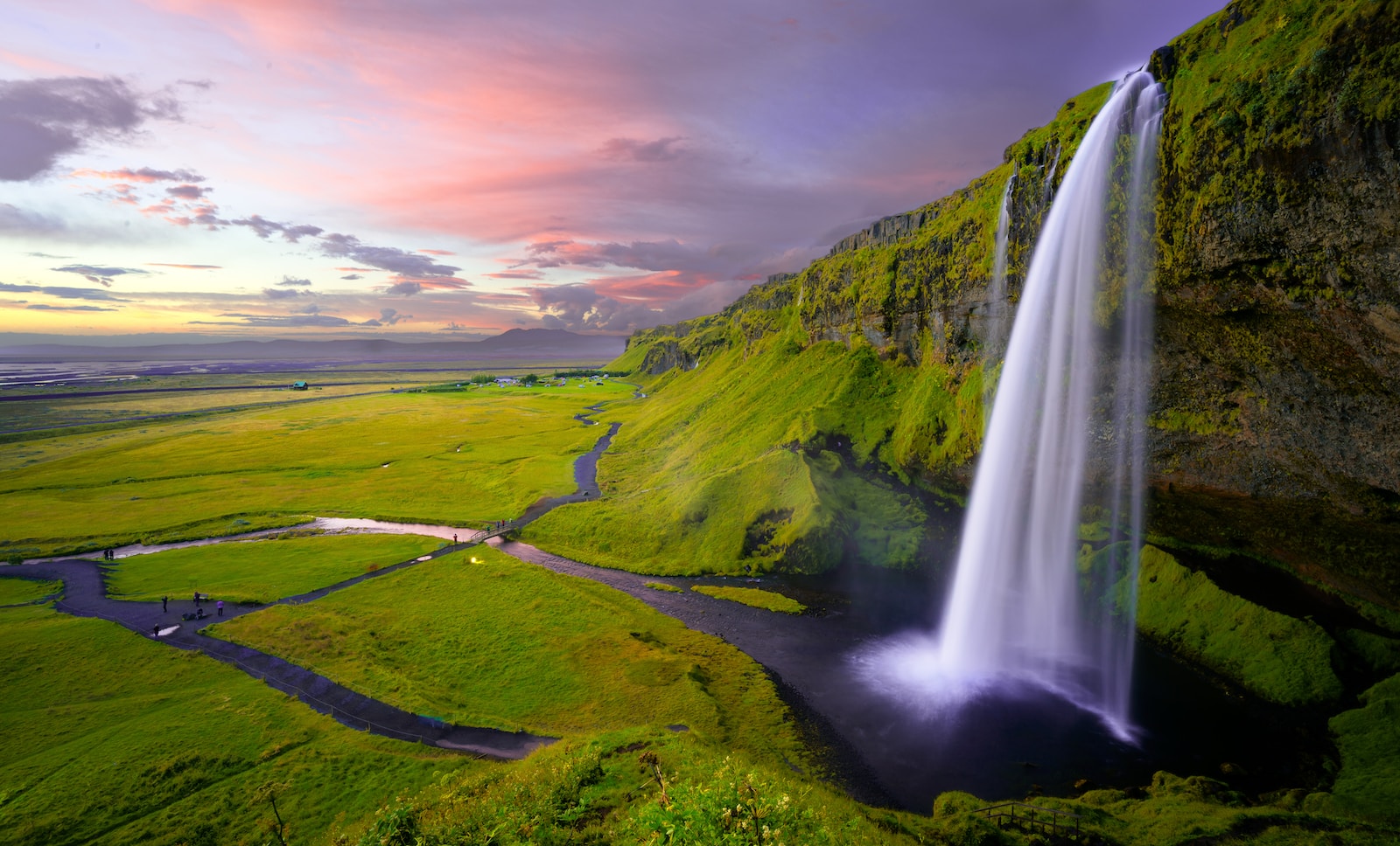 waterfalls in the middle of green grass covered mountain